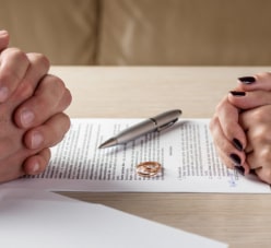 Two Hands On A Piece Of Paper And A Golden Ring Between Them